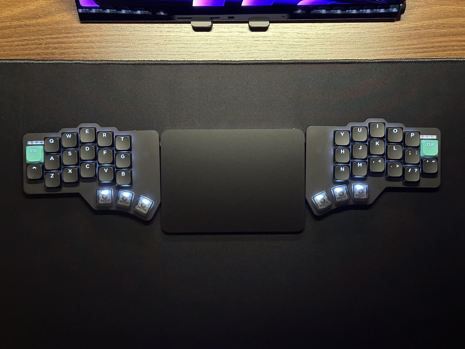 The finished split keyboard beside a trackpad on a dark desk
